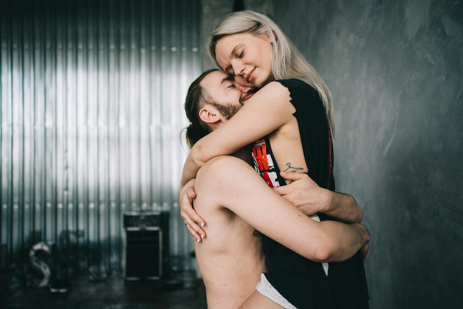 A young couple shares a tender embrace in a stylish indoor setting.