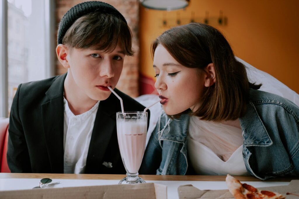 A young couple shares a milkshake in a cozy café, enjoying the moment together.