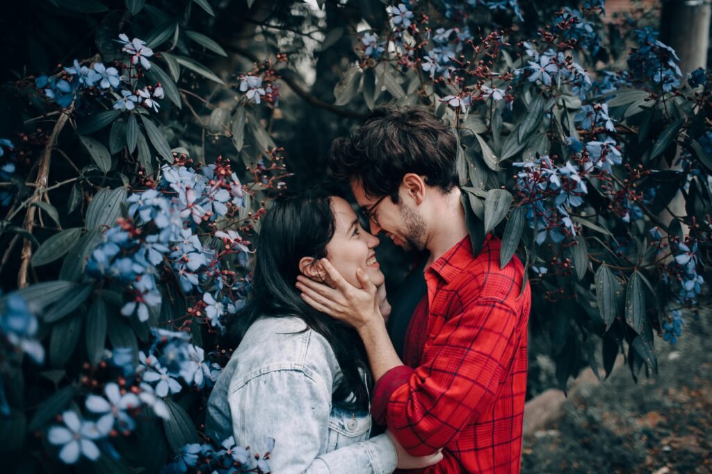 A young couple in love embraces amidst vibrant flowers, exuding romance and happiness outdoors.