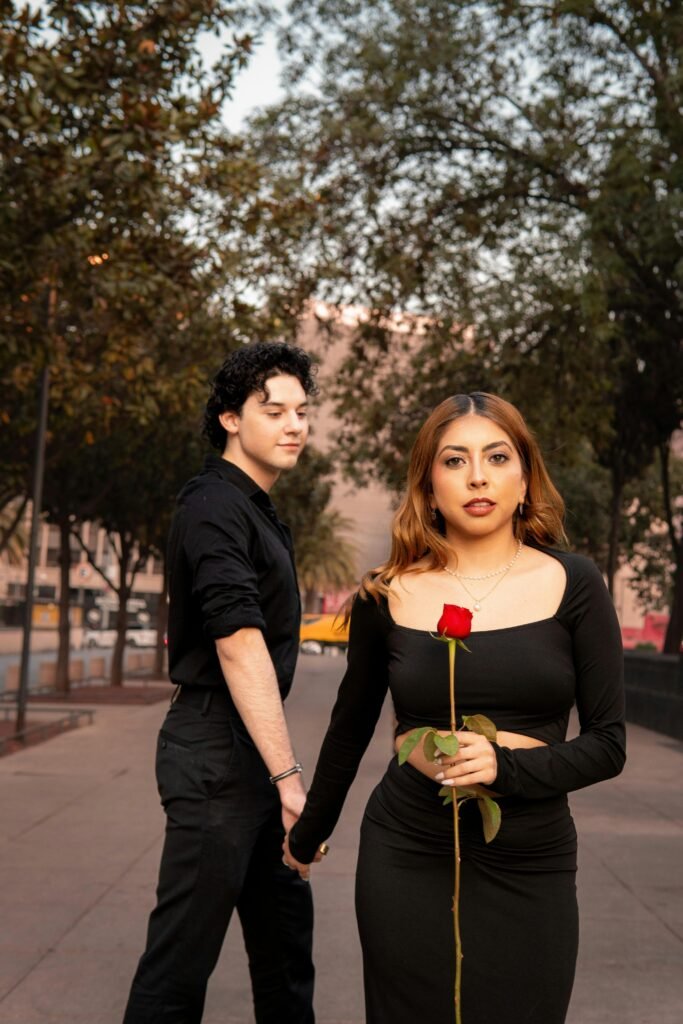 A couple holds hands with a single red rose on a sunny day in Mexico City.